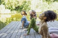 Group of teenages is engaged in fitness on pier by the lake or river. Young and positive girls go in for sports