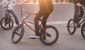 Group of teens on Bmx bikes in a skate park at sunset. Legs and bmx at sunset. bmx concept Royalty Free Stock Photo