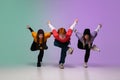 Group of teens, boys and girls dancing hip-hop in stylish clothes on gradient studio background in neon light. Royalty Free Stock Photo