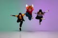 Group of teens, boys and girls dancing hip-hop in stylish clothes on gradient studio background in neon light. Royalty Free Stock Photo