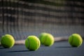 A group of tennis ball on a court with net in background