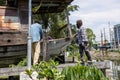 A group of Thai male workers are installing large rope slings to lift and move an old wooden boat