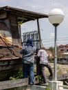 A group of Thai male workers are installing large rope slings to lift and move an old wooden boat