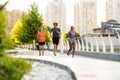 Group of three active people running together outdoors on bridge