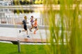 Group of three active people running together outdoors on bridge