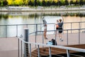 Group of three active people doing workout outdoors on bridge