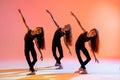 group of three ballet girls in black tight-fitting suits dancing on red background with their long hair down