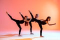 Group of three ballet girls in black tight-fitting suits dancing on red background with their long hair down