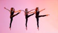 group of three ballet girls in black tight-fitting suits jumping on red background with their long hair down Royalty Free Stock Photo