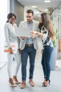 Group of three business people with laptop having informal meeting in office hall. Royalty Free Stock Photo