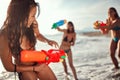 Group of three female friends playing with water guns on the sandy beach Royalty Free Stock Photo