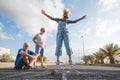 Group of three caucasian people having fun and playing at the hopscotch together - beautiful woman jumping in the middle of the