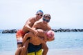 Group of three friends having fun playing and enjoying together at the beach wearinng sunglasses laughing smiling and looking at Royalty Free Stock Photo