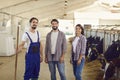 Happy workers looking at camera and smiling after feeding cows and cleaning cowshed on dairy farm Royalty Free Stock Photo