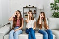 Group of three hispanic girls sitting on the sofa at home doing ok gesture shocked with surprised face, eye looking through Royalty Free Stock Photo