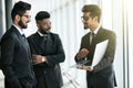Group of three indian business man in suits looking at laptop standing in modern office hall at informal meeting Royalty Free Stock Photo