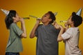 Group of three intercultural pre-teen children blowing whistles