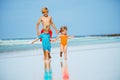 Group of three kids run on sand beach holding hands Royalty Free Stock Photo