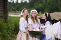 Group of Three Laughing Caucasian Girls Standing Together in Traditional Rural Costumes With Basin of Linens at Countryside Royalty Free Stock Photo