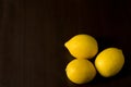 Group of three lemons in corner on dark background