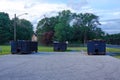 A group of three long blue dumpsters full of construction debris in a parking lot
