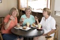Group of three lovely middle age senior mature women girlfriends meeting for coffee and tea with cakes at coffee shop sharing time