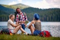 group of three, man and two women, taking a break by the lake, talking, laughing Royalty Free Stock Photo