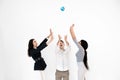 Group of three multiethnical international happy people throwing up little globe earth and looking up while it is Royalty Free Stock Photo