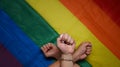 Three people making power fist gesture on pride LGBT rainbow flag.