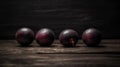 a group of three plums sitting on top of a wooden table next to each other on top of a wooden table next to a black wall