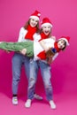 Group of Three Positive Caucasian Girls With Santa Hats Having Fun While Lifting Teenage Girl Holding Hands Closed Against Trendy Royalty Free Stock Photo