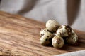 Group of three quail eggs on piece of wood over homespun tablecloth, top view, selective focus, backlight. Royalty Free Stock Photo