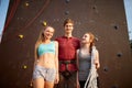 Group of three rock climbers with safety equipment smiling and looking at camera against artificial climbing wall Royalty Free Stock Photo