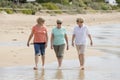 Group of three senior mature retired women on their 60s having fun enjoying together happy walking on the beach smiling playful Royalty Free Stock Photo