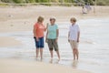 Group of three senior mature retired women on their 60s having fun enjoying together happy walking on the beach smiling playful Royalty Free Stock Photo