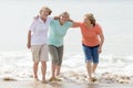 Group of three senior mature retired women on their 60s having fun enjoying together happy walking on the beach smiling playful Royalty Free Stock Photo