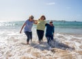 Group of three senior women laughing as falling down in the water on beach. Humor senior health