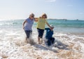 Group of three senior women laughing as falling down in the water on beach. Humor senior health