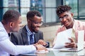 A group of three stylish African American businessman partners entrepreneurs in fashion business suits meeting sitting