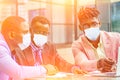 A group of three stylish African American students entrepreneurs in fashion business suits working sitting at table with Royalty Free Stock Photo