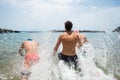 Group of three teenagers and young men enjoying summer vacations in the beach swimming and running to the sea or ocean smiling and Royalty Free Stock Photo