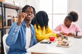 Group of three young black people sitting on a table having coffee surprised with an idea or question pointing finger with happy Royalty Free Stock Photo