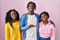 Group of three young black people standing together over pink background smiling cheerful presenting and pointing with palm of Royalty Free Stock Photo