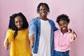 Group of three young black people standing together over pink background smiling friendly offering handshake as greeting and Royalty Free Stock Photo