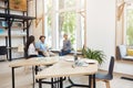 Group of three young multi ethnic startups working together in coworking space, having break from brainstorming. Young Royalty Free Stock Photo