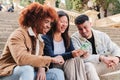 Group of three young multiracial friends smiling and having fun using a social media app on smartphone. Happy teenagers Royalty Free Stock Photo