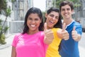 Group of three young people in colorful shirts standing in line and showing thumbs Royalty Free Stock Photo