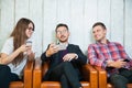 Group of three young people hold smartphones talk and smile
