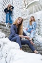 Group of three young Stylish nice girls in pantsuit costumes sitting on a stairs near white construction Royalty Free Stock Photo