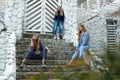 Group of three young Stylish nice girls in pantsuit costumes sitting on a stairs near white construction Royalty Free Stock Photo